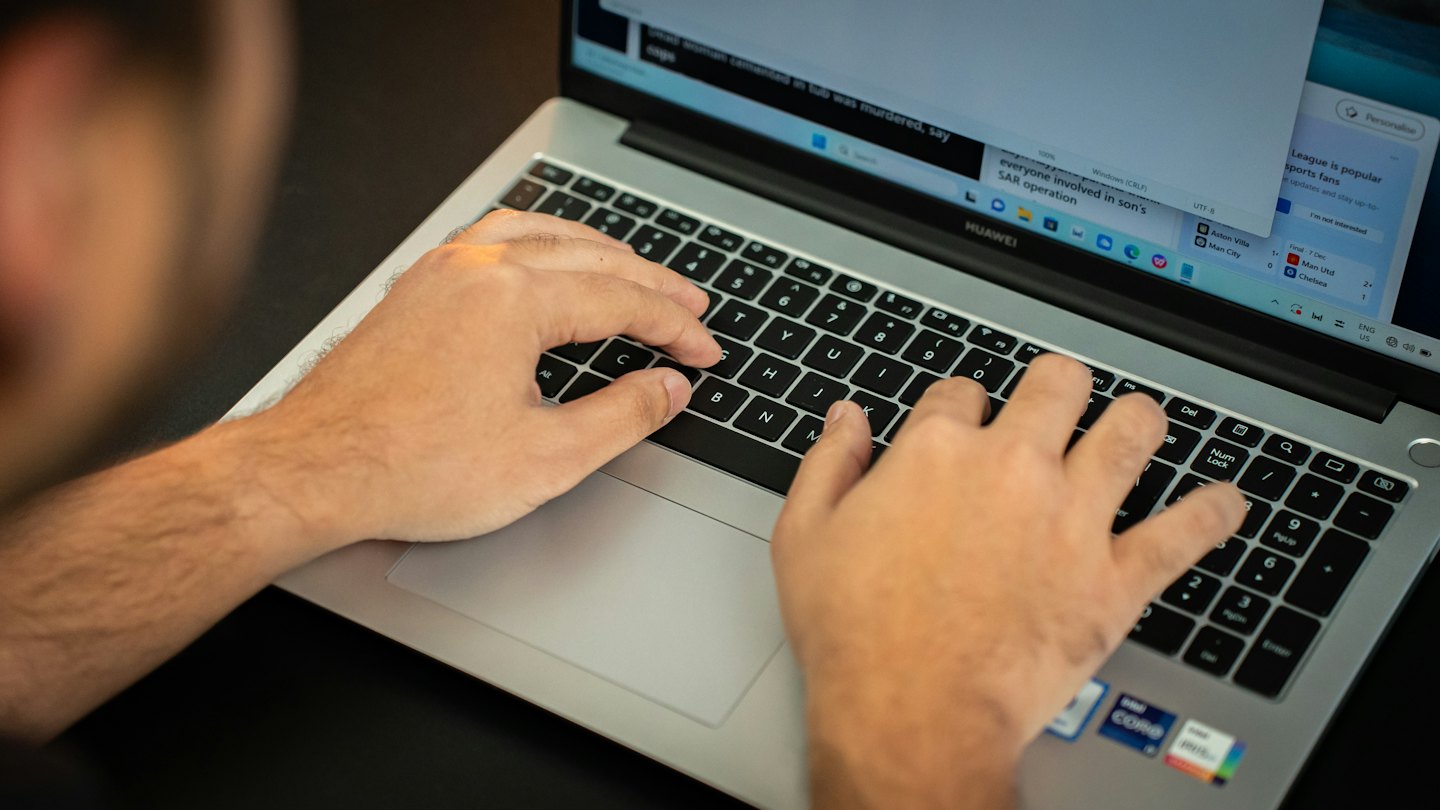 Una persona digita su un portatile che mostra informazioni e titoli.